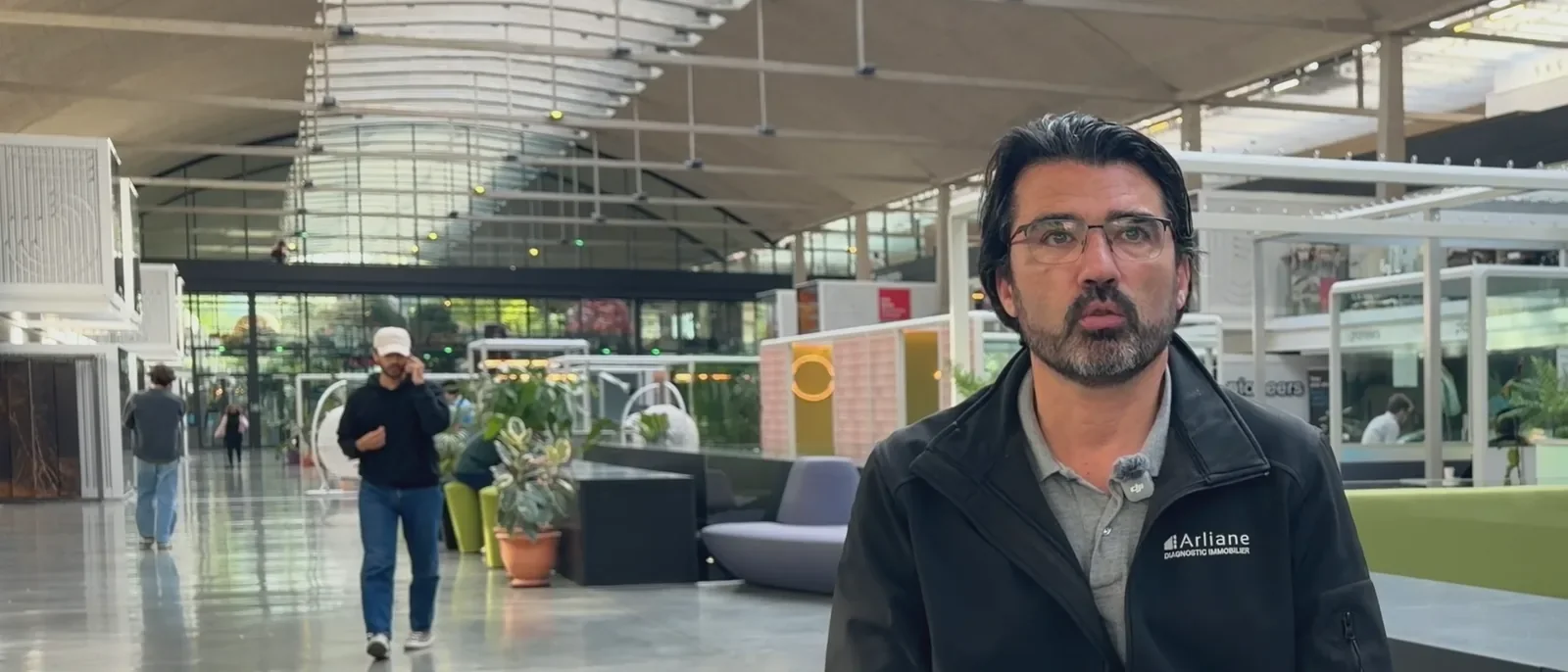 Fabien Candus, diagnostiqueur immobilier, assis sur un tabouret dans un grand hall lumineux, pendant son interview